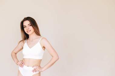 20 'li yaşlarda güzel bir kadın bejde izole edilmiş kameraya bakıyor. Genç bir kadının yakın plan portresi. Sağlıklı vücut bakımı, genç yaşta cilt bakımı kozmetik ürünleri, kozmetoloji konsepti