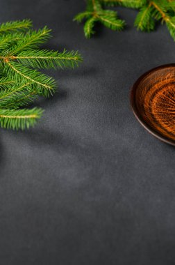 Sol köşede Canlı Noel Ağacı dalları olan dikey Gri Arkaplan. Sağ köşedeki kil tabaka kahverengi-turuncu. Noel Teması