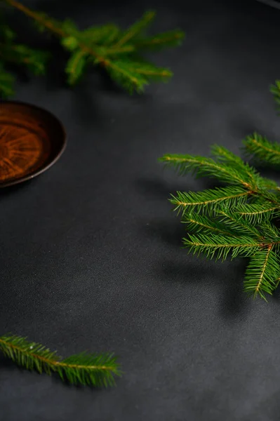 Vertical screensaver with a Clay Plate and Green Christmas tree branches on a dark gray Background. Christmas concept. Copy Space.