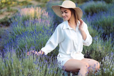 Beyaz Pamuklu Giysili Genç Kadın, Akşam Lavanta Tarlası 'nda oturuyor. Şapkalı Beyaz Kız Elini Lavanta Çalıları 'ndan Geçiriyor.