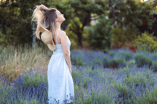Woman in Sundress Enjoys Life Inhaling Fresh air in Lavender Meadow Against Natural Background. Concept of Medicinal Properties of Lavender. Hair Care