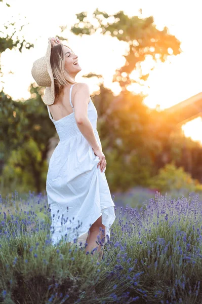 Woman in Hat, Sundress Rejoices in Life in Lavender Meadow Against Backdrop of Orange Sun. Golden Sun is Setting.
