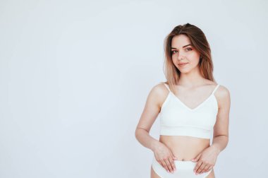 Kusursuz figürlü genç bir kadın izole edilmiş beyaz bir arka planda duruyor. Kız spor için iç çamaşırı giyiyor. Kadın Özel Sağlığı.