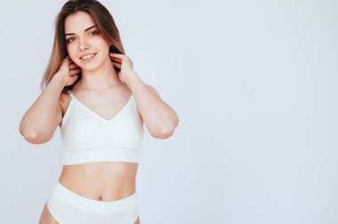 Kusursuz vücutlu genç kadın portresi beyaz izole edilmiş arka planda duruyor. Beyaz spor iç çamaşırlı kız. Kadın Özel Sağlığı.