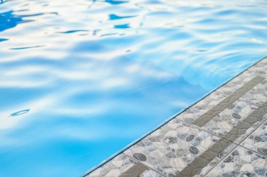 Real Estate, Property or Hotel Stylish Swimming Pool. An Empty Swimming Pool from Luxury Home with Stone Tiles Around and Clear Transparent Turquoise Blue Water.