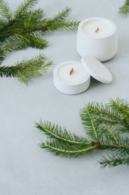 Bir grup beyaz mum çeşitli boyutlarda beton kapta Noel Ağacı dalları arasında hafif arka planda Lid ile. Yumuşak Bulanık Odaklanma. Masanın üzerindeki firavun dalları. Noel Konsepti