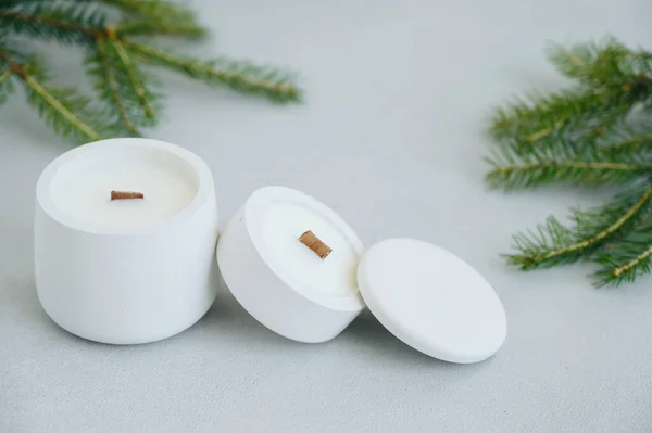Close-up of Group of White Candles in Concrete Pot of Various Sizes With Lid on Light Background. Soft Blurry Focus. Fir Branches on Table. Place Under Label on Candle.