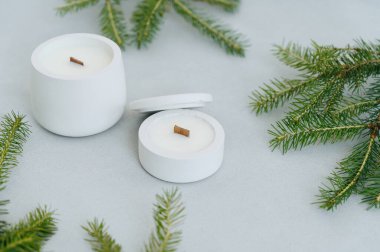 Farklı boyutlarda beyaz mumlar ve ön görüş kapakları. Açık Gri Arkaplan 'da Yılbaşı Ağacı Dalları ve Mumları Yatıyor. Etiket 'e yer var. Noel Teması