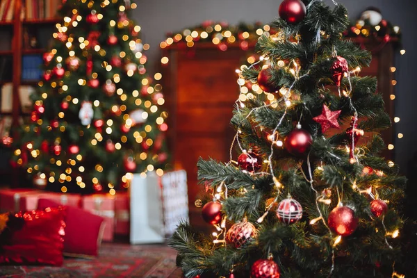 Evergreen Noel Ağacı kırmızı oyuncaklar ve parlak çelenklerle süslenmiştir. Arkadaki Sarı Bokeh Çelenkleri. Konforlu Noel İçi