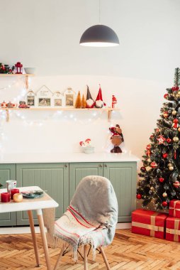 Cozy Provencal Kitchen on New Year's Eve with Christmas Tree, Gifts and Cute Christmas Decor. Light is on In Kitchen Above Table.