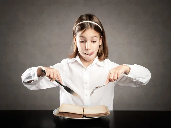 Menina com fome na frente de um livro — Fotografia de Stock