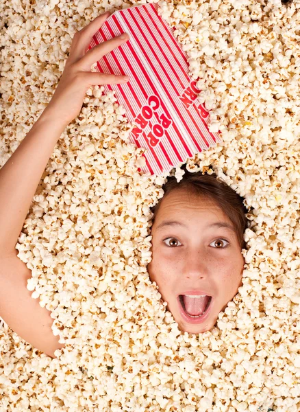 Jong meisje begraven in popcorn — Stockfoto