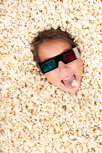 Jong meisje begraven in popcorn Stockfoto