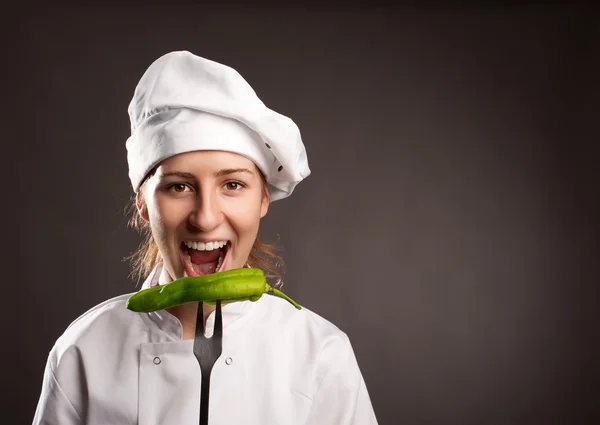 Mulher chef segurando uma pimenta verde — Fotografia de Stock