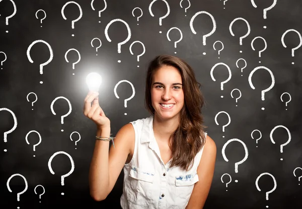 Mujer joven sosteniendo una bombilla con símbolos de interrogación — Foto de Stock