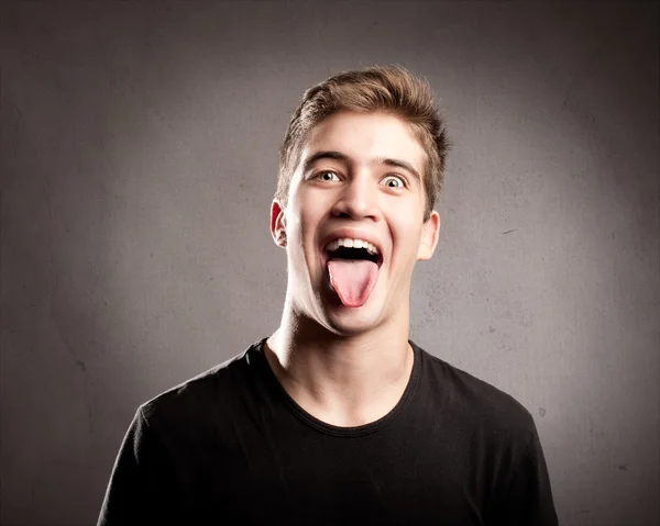 Young man showing tongue — Stock Photo, Image