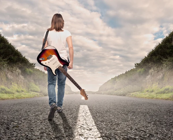Jonge musicus vrouw lopen op een weg — Stockfoto