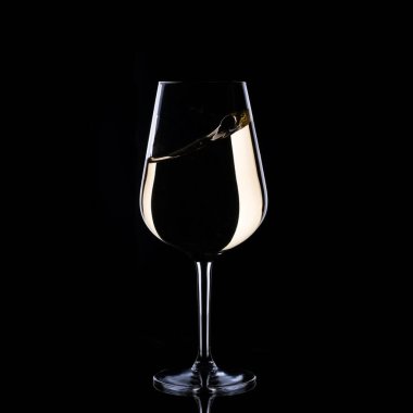 white wine splash in glass isolated on black background. High quality photo