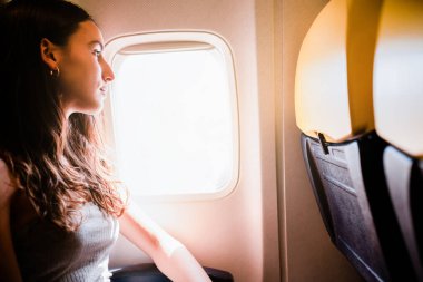 young girl looking through the window while traveling on airplane. High quality photo