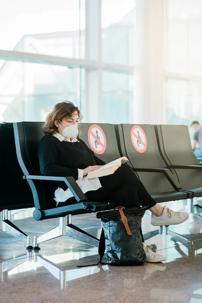 Mature Tourist Woman Wearing Face Mask Reading Book Airport While 图库图片