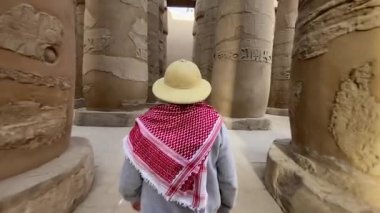 back view of woman walking among the columns with hieroglyphs inside the Karnak Temple, in Luxor Egypt. High quality 4k footage