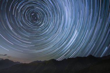 silhouetted mountains with circumpolar star trails in northern sky. High quality 4k footage