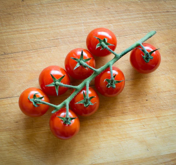 Tomatoes on brown textured wood — Stock Photo, Image