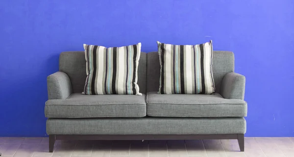 Graues Sofa auf blauem Stuck — Stockfoto