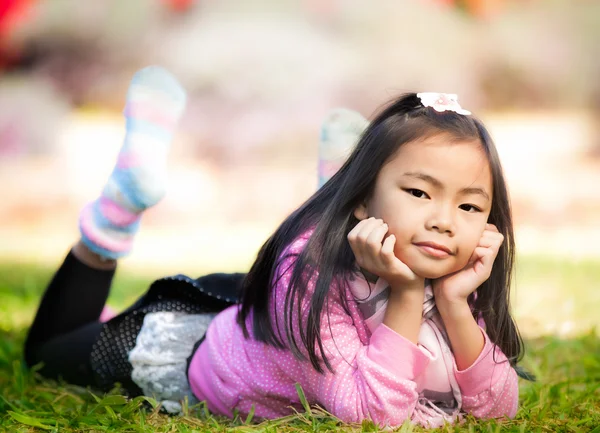 Little asian girl resting on green grass — Stock Photo, Image