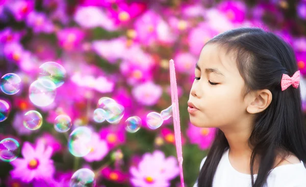 Asiático niña es soplando un jabón burbujas — Foto de Stock