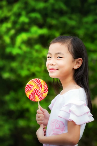 Asian girl eating a colorful candy — Stock Photo, Image