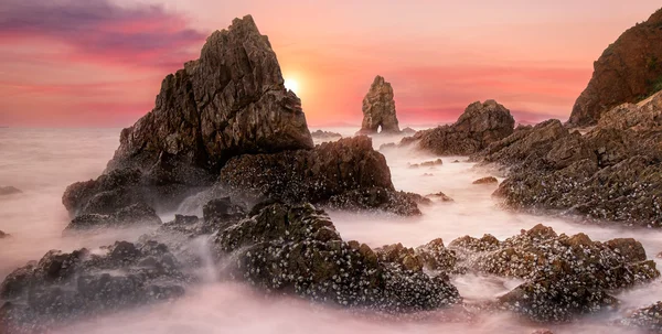 Havet våg slå berget vid solnedgången — Stockfoto