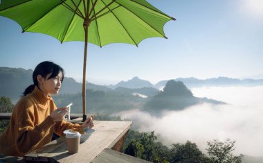 Kameralı Asyalı gezgin, Japo köyündeki bir dağda, kahve ve çay setinde sis için fotoğraf çekiyor. Tayland 'lı mae hong oğlu.