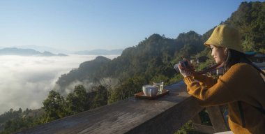 Kameralı Asyalı gezgin, Japo köyündeki bir dağda, kahve ve çay setinde sis için fotoğraf çekiyor. Tayland 'lı mae hong oğlu.