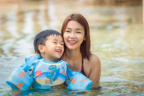 小さな男の子とともにお母さんリラックスしてプールで日当たりの良い日 — ストック写真