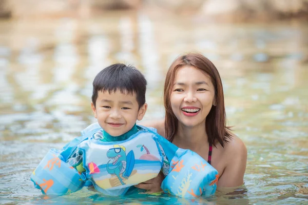 小さな男の子とともにお母さんリラックスしてプールで日当たりの良い日 — ストック写真