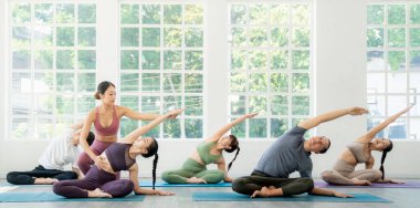 Asian yoga trainer and her student pose yoga basic position in her class room in fitness center