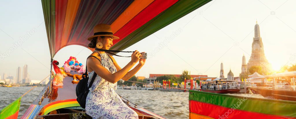 Asian traveller girl take a Wat arun photo from traditional long tail boat in Bamgkok city, Thailand