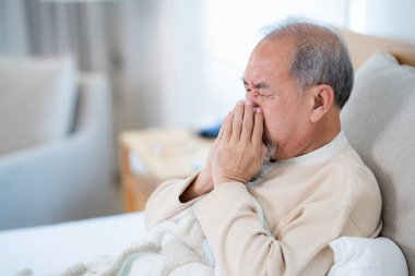 Yaşlı adamda çovid virüsü var ve evindeki yatakta karantinaya alınıyor. Yaşlı adam öksür ve yatakta uyu..