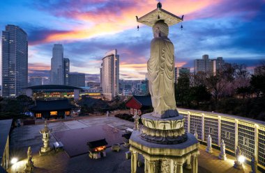 A giant Buddha statue looks out over downtown Seoul at sunset from Bongeunsa Temple, South Korea