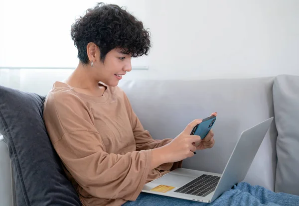 Latin woman shopping online by application in computer note book and pay monry online by credit card on sofa