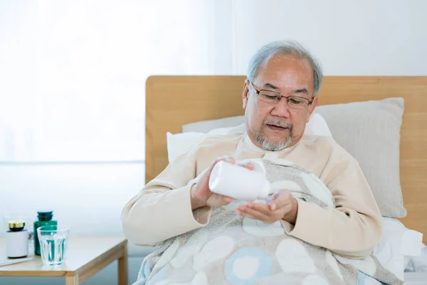 Asian Old man eating drug on the bed at home, This photo can use for drug, medicine, pharmacy and insurance concept