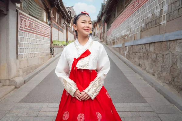 Asian woman traveler in traditional korean dress or hanbok dress walking in old palace with sakura flower background, Seoul city, South Korea