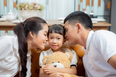Asyalı bir aile, evde klasik kanepe ile oturma odasında film izlemekten zevk alır.