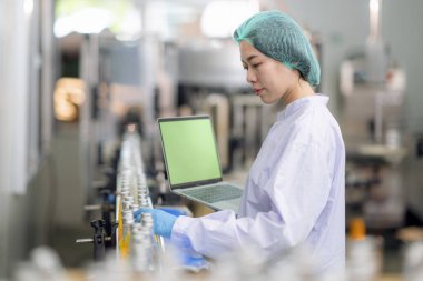 Asyalı profesyonel gıda bilimcisi gıda indüksiyon fabrikasındaki kimya laboratuvarında içeceğin kalitesini kontrol ediyor ve kontrol ediyor