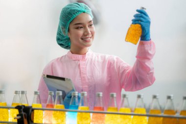Asyalı profesyonel gıda bilimcisi gıda indüksiyon fabrikasındaki kimya laboratuvarında içeceğin kalitesini kontrol ediyor ve kontrol ediyor