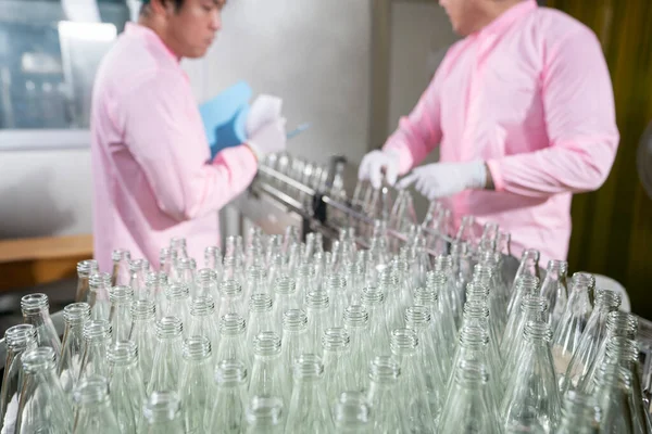 工場内の飲料産業の生産ラインで自動搬送機の生ガラス瓶で働くアジア人オペレーター — ストック写真