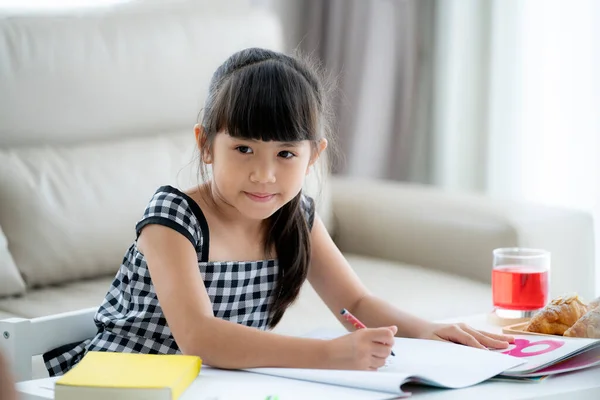 アジアの就学前の女の子は自宅のリビングルームで彼女の家の仕事をしています — ストック写真