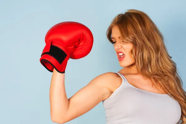 Beautiful woman flexing arm muscles wearing a boxing glove — Stock Photo, Image