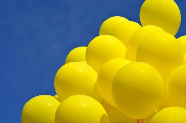 Sarı balonlar mavi gökyüzü arka planına karşı festivalde